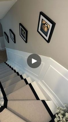 a staircase with pictures on the wall and carpeted steps leading up to it's second floor