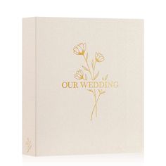 a white wedding album with gold lettering and flowers