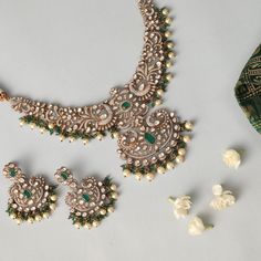 Description : Presenting our opulent floral and peacock motif necklace and earring set. This exquisite ensemble showcases meticulous craftsmanship, with moissanites and cubic zirconia stones arranged into intricate floral and peacock motifs, enhanced by Victorian plating for an added touch of old-world charm. The necklace drapes gracefully, adorned with green semi-precious gemstones and hanging pearls, while the matching earrings complete the look with similar motifs, offering a rich and regal e Festive Diamond Jewelry Set With Intricate Design, Elegant Jewelry Sets With Peacock Design And Chandbali Shape, Elegant Kundan Necklace With Peacock Design For Festive Occasions, Festive Bridal Necklace With Intricate Cubic Zirconia Design, Elegant Kundan Bridal Necklace With Peacock Design, Temple Jewelry Sets With Intricate Diamond Design, Traditional Jewelry Sets With Diamond Accents, Elegant Festive Jewelry Sets With Peacock Design, Temple Jewelry Diamond Sets With Intricate Design