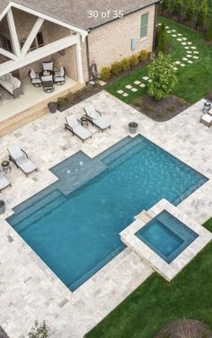 an aerial view of a swimming pool with lounge chairs around it and grass in the yard