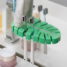 three toothbrushes are sitting on a green holder