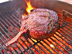 a steak is cooking on the grill with flames coming out of it's side