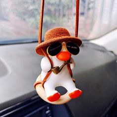 a snowman ornament hanging from the dashboard of a car wearing sunglasses and a hat