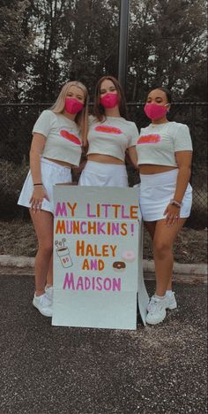 three women in matching outfits holding a sign that says my little munchkinss haley and madison