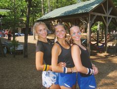 three girls standing together in front of a gazebo with their arms around each other