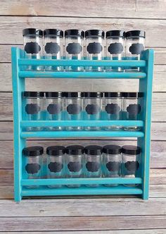 a blue shelf with several jars on it and one is filled with black lids, while the other holds silver cups