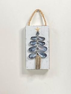 a wooden plaque with a christmas tree painted on it's side hanging from a rope