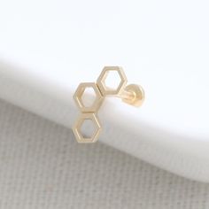 two hexagon shaped gold rings sitting on top of each other in front of a white surface