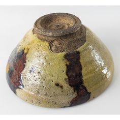 a brown and black vase sitting on top of a white table