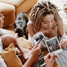 two women are sitting on the floor and one is looking at photos with her dog