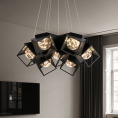 a modern chandelier hanging from the ceiling in a living room with black curtains