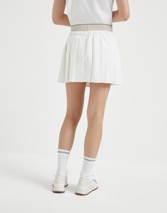 Pleated techno poplin mini skirt with tennis logo The sporty yet elegant feel of the world of Tennis inspires a selection of creations that enrich the Women's collection. The techno poplin pleated skirt, inspired by the style of the designs worn on the sidelines, features a practical elastic waistband in contrasting colors and a pair of built-in shorts that provide added comfort. The racket embroidery detail reinterprets the Brunello Cucinelli logo and crest with a personalized touch. Preppy Cotton Short Tennis Skirt, Classic White Tennis Skirt For Summer, White Tennis Mini Skirt, Classic White Tennis Dress For Spring, White Cotton Tennis Bottoms, Tennis Mini Skirt With Lining, Spring Tennis Shorts With Pleated Skirt, Classic White Tennis Skirt For Spring, Classic White Tennis Skirt