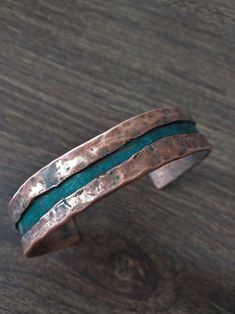 a copper and green ring sitting on top of a wooden table