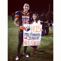 a man and woman holding a sign on the field