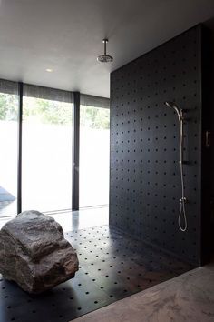 a large rock sitting next to a shower in a room with black walls and flooring