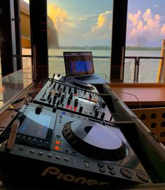 a laptop computer sitting on top of a dj's desk in front of a window