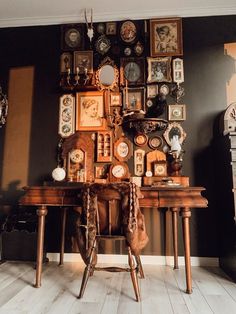 a room with many pictures on the wall and two wooden tables in front of it