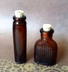 two brown glass bottles sitting next to each other on top of a tablecloth covered floor