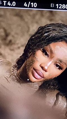 an image of a woman in the water with her face covered by mud and sand