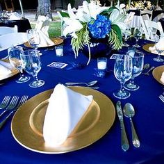 the table is set with blue and gold plates, silverware, and napkins