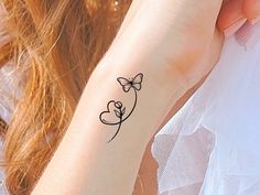 a woman's arm with a tattoo on it that has a butterfly and heart