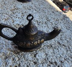 a black teapot sitting on top of a sidewalk