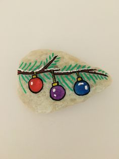 a rock with ornaments painted on it sitting on top of a white table next to a tree branch