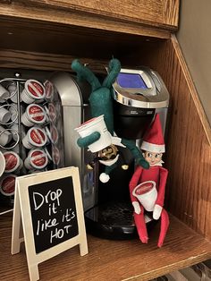 two elfs sitting on top of a shelf next to a coffee maker and soda machine