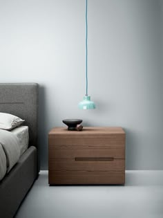 a bedroom with a bed, nightstand and blue light hanging from the ceiling over it