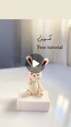 a small toy rabbit sitting on top of a white block with the caption free tutor