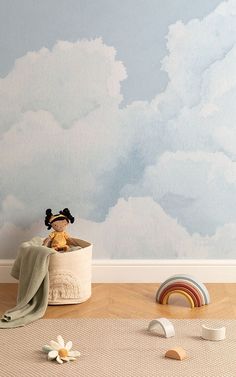 a child's room with clouds painted on the wall and toys scattered around it