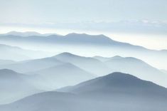 the mountains are covered in fog as seen from an airplane