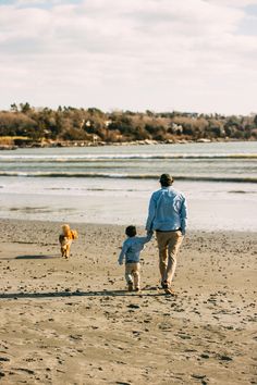 a man and child are walking on the beach