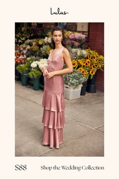 a woman standing in front of flowers wearing a pink dress