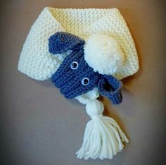 a white and blue knitted hat with pom - pom on it sitting on top of a table