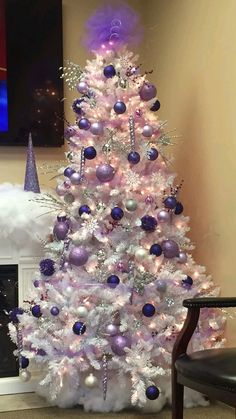 a white christmas tree with purple and silver ornaments