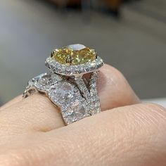 a close up of a person's hand holding an engagement ring with yellow and white diamonds