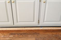 a kitchen with white cabinets and wood flooring on the bottom part of the cabinet