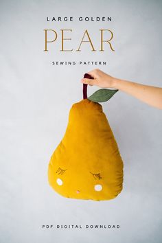 a hand holding a yellow stuffed animal with leaves on it's head and the words pear sewing pattern