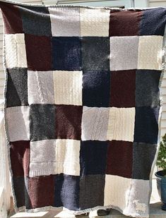 a blanket that is sitting on top of a wooden bench next to a potted plant