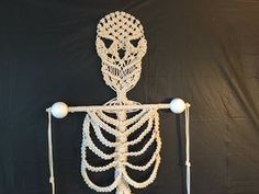 a skeleton made out of string and beads on a black background with a white light bulb