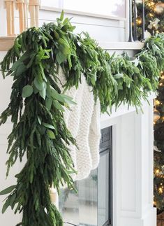 the stockings are hung on the mantle with greenery and lights in the fireplace mantel