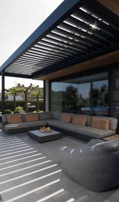 a large couch sitting on top of a patio next to a table and chairs under a pergolated roof