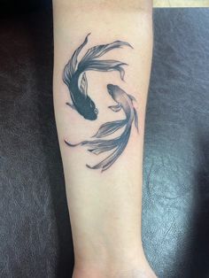 a black and white koi fish tattoo on the wrist