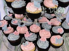 cupcakes with pink and blue frosting on a cake stand