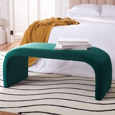 a green bench sitting on top of a white rug next to a neatly made bed