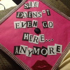 a pink graduation cap with words written on the front and bottom that says she doesn't even go here anymore