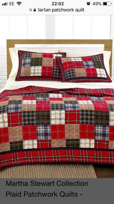 a bed with red and black plaid quilts on it's cover, next to a rug