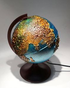 a colorful globe on top of a wooden stand with a cord attached to the base