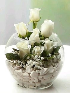 a bowl filled with rocks and flowers on top of a table